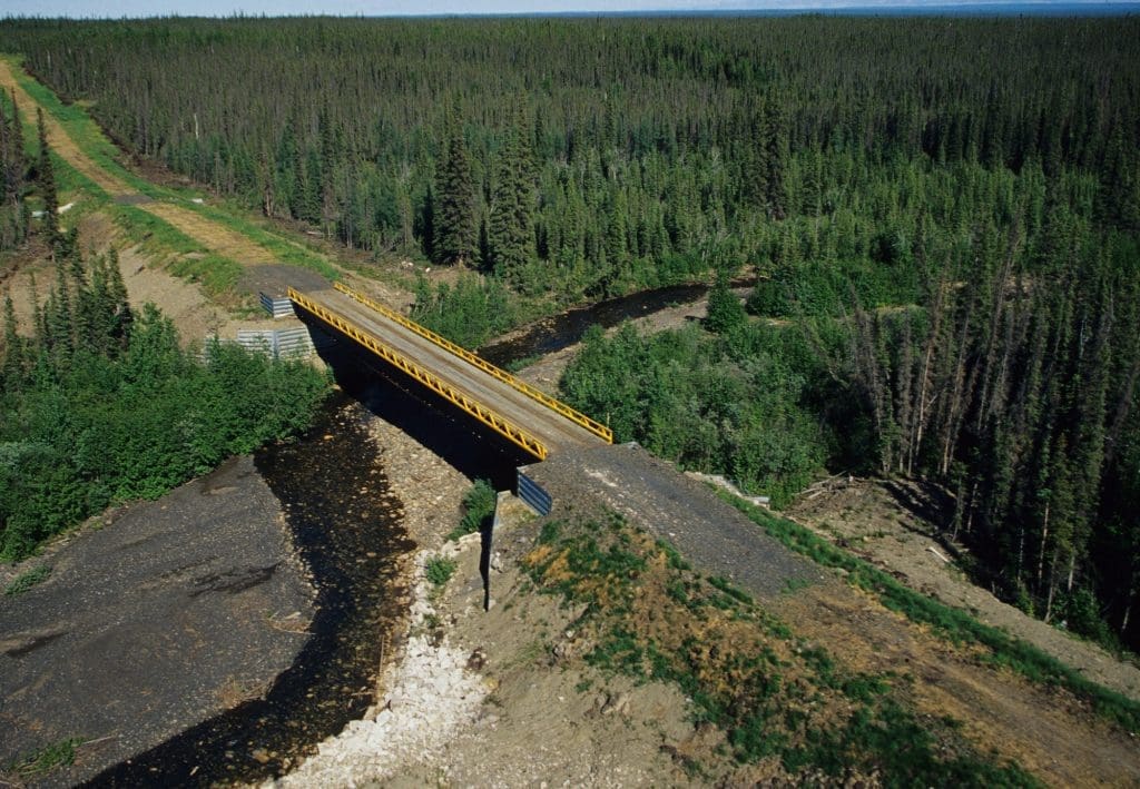 A bridge crosses a river in the boreal forest