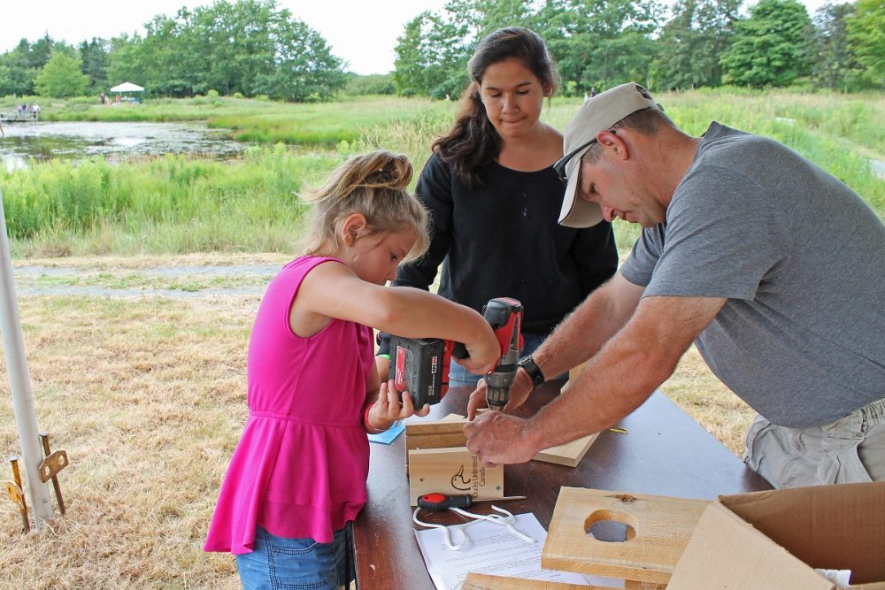 A volunteer helps a young girl build a nest box at a DUC event in Nova Scotia.