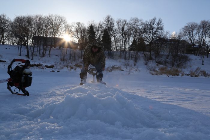 Pat Kehoe drills holes into the ice for a morning of fishing. Despite minus 34 C temperatures, Kehoe completes the task without gloves or a hat.