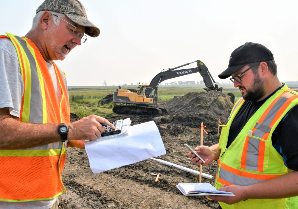 DUC engineer Dave Dobson (left) and fellow engineer, Patrick Lederman, check elevations at the work site about 40 kilometres northwest of Brandon.