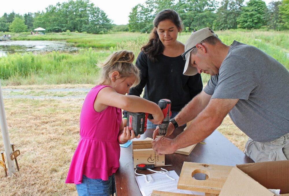 A volunteer helps a young girl build a nest box at a DUC event in Nova Scotia.