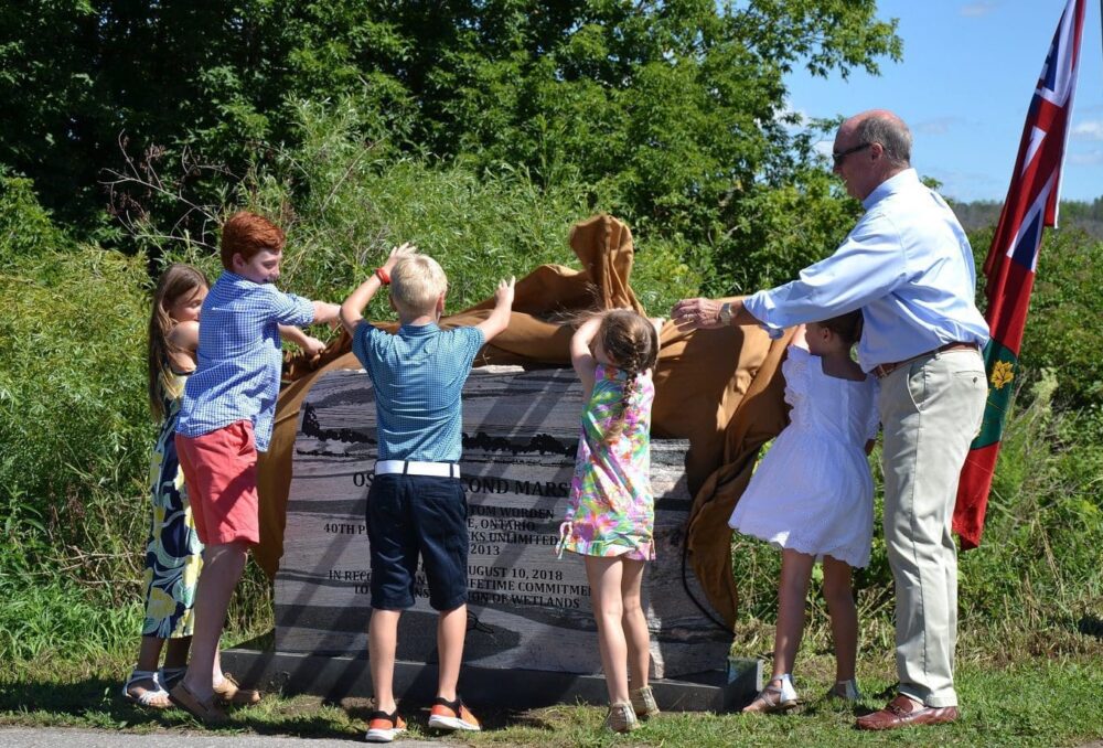 Tom Worden unveils the cairn at Oshawa Second Marsh, with help from grandchildren Hayden, Jack, Lauren, Paige and Kate. 