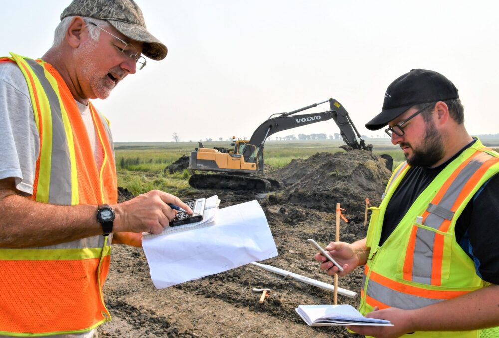 DUC engineer Dave Dobson (left) and fellow engineer, Patrick Lederman, check elevations at the work site about 40 kilometres northwest of Brandon.