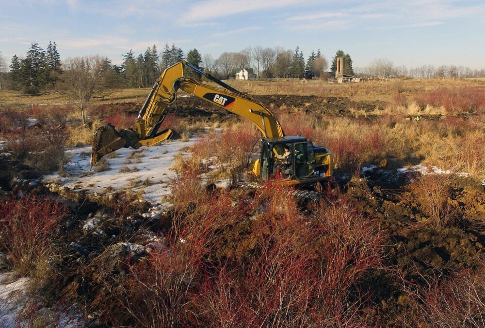 FRAMED BY THE TRIBE FAMILY HOMESTEAD, NICK SWEAZEY DIGS AMONGST THE RED SCRUBBY BRUSH, CLOSE TO THE BANKS OF BIG CREEK.