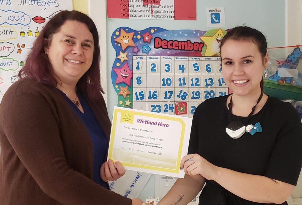 Ducks Unlimited Canada Education Specialist for NB and PEI Samantha Brewster shakes hands with Park Street Elementary School student-teacher Molly McIntyre while presenting her a Wetland Hero certificate on December 13, 2019 in Fredericton, N.B. McIntyre is currently enrolled in St. Thomas University, finishing a post-bac in education.