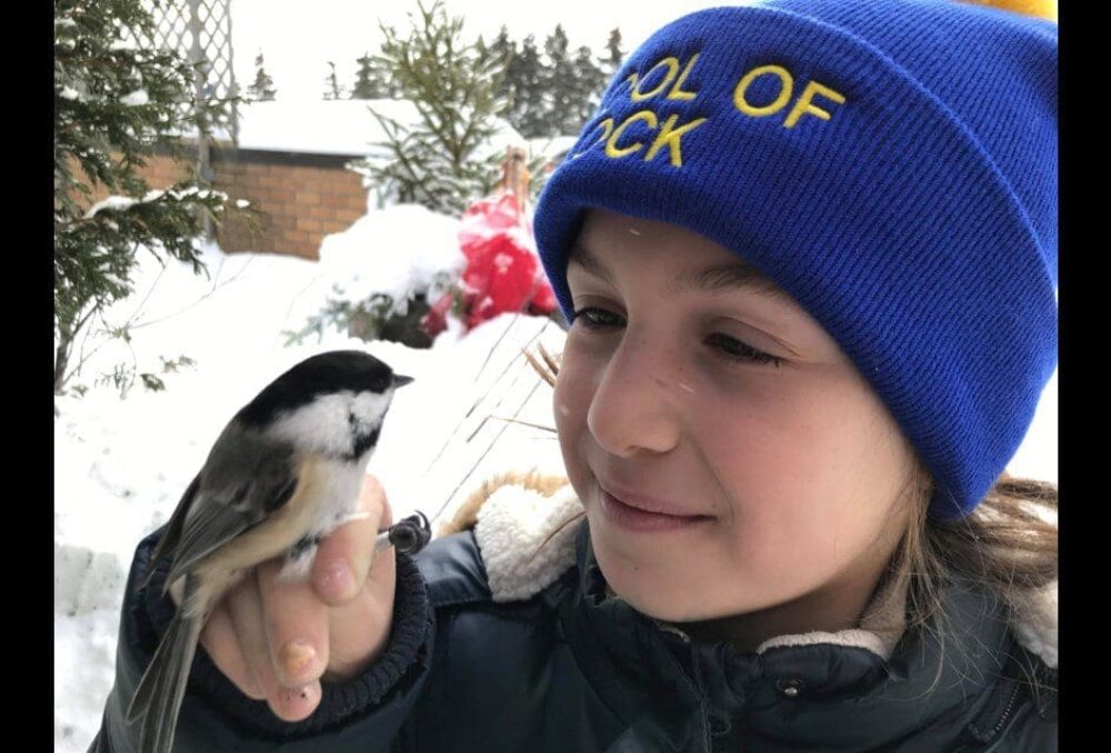 DUC Wetland Hero Lucy Harrison poses with a chickadee at Hilliardton Marsh, Ontario. Harrison learned her bird-handling skills as a volunteer and demonstrates the techniques to younger children. 