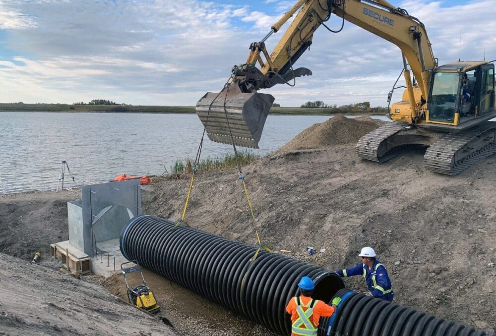 Workers install pipe at the DUC project at Bars Lake near Kenton.