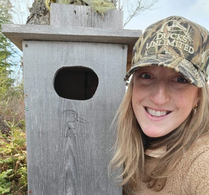 DUC volunteer Angèle Scott poses with a nest box installed in Shelburne County.