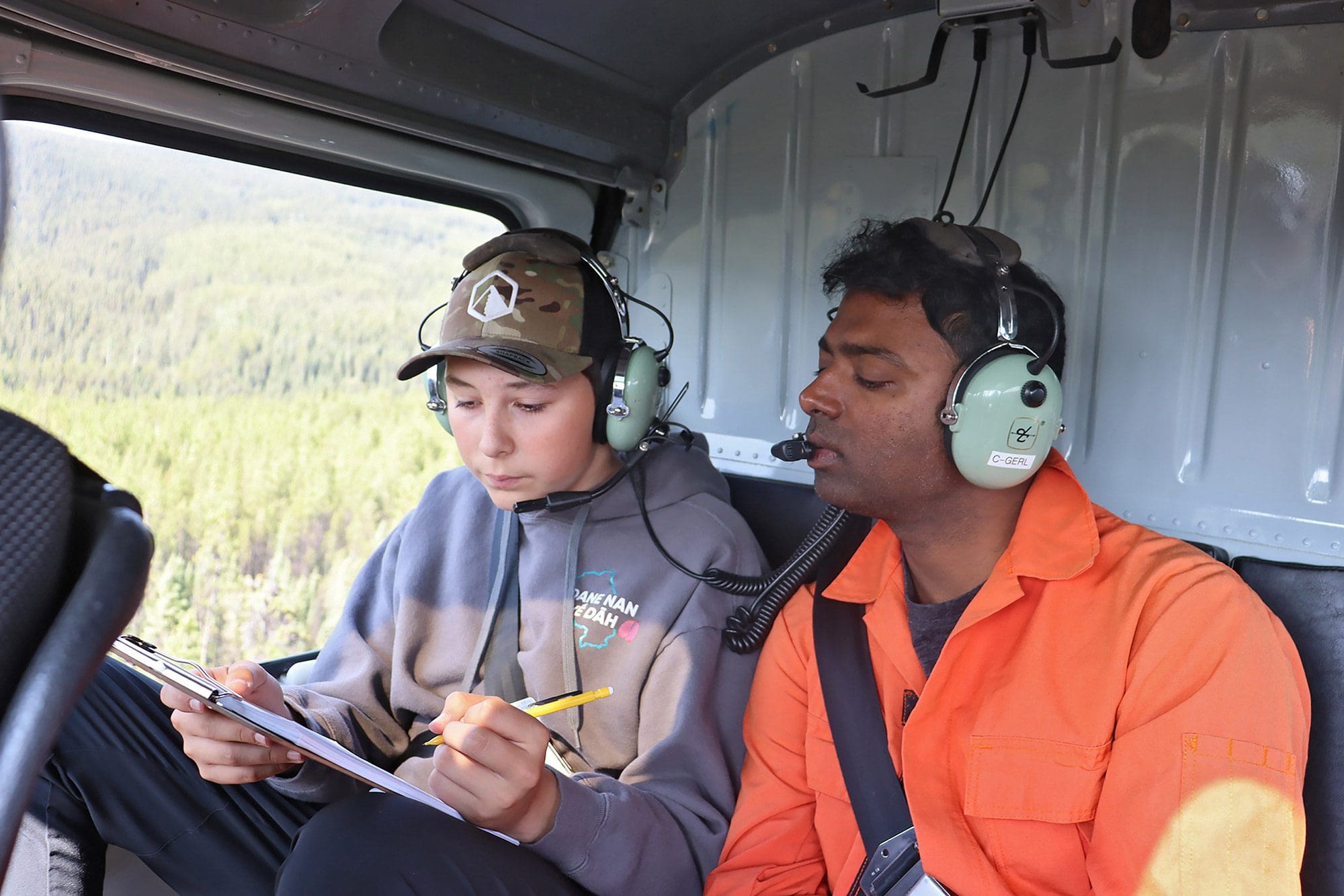 Environmental Solutions: Kaska Land Guardian Daniel Koehl and Ducks Unlimited Canada's James Varghese record wetland information during a helicopter survey.