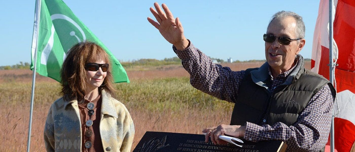 Long-time DUC employee and conservation leader Rick Andrews waves to the crowd, with his wife Judy, at the land dedication ceremony (September 2022) north of Brandon.