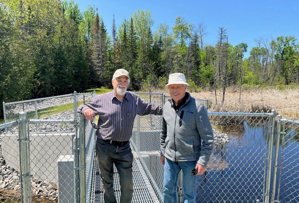 Munroe and Ray Scott standing at the water control structure at the wetland on their property.