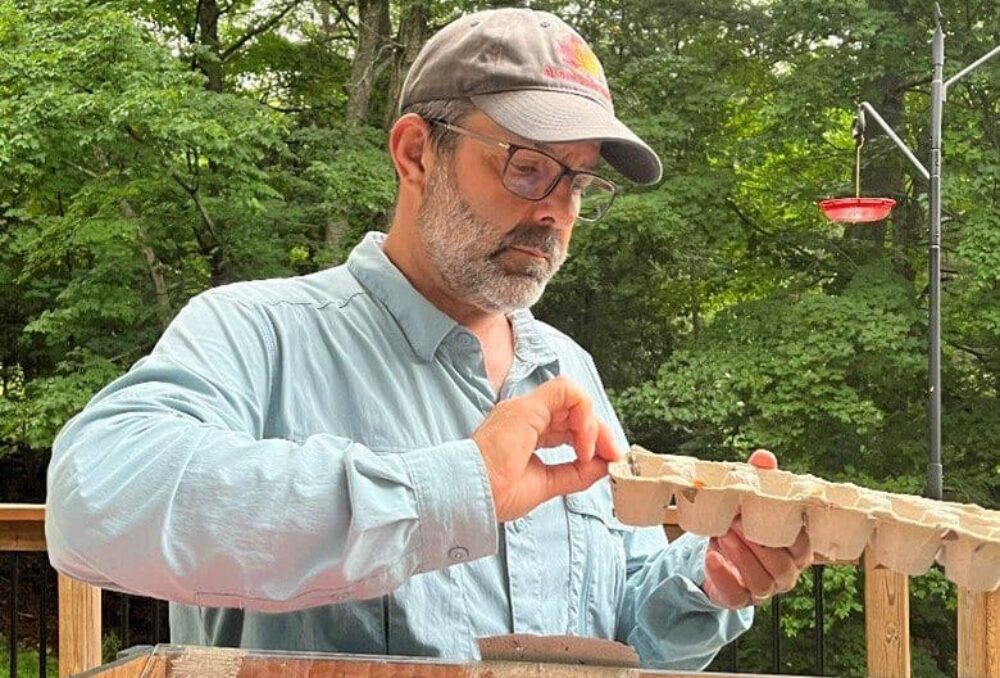 Moth enthusiast Ed Poropat examines a moth trap in his backyard. Egg cartons are used to provide captured moths with a textured surface and a variety of gaps and crevices to roost inside.