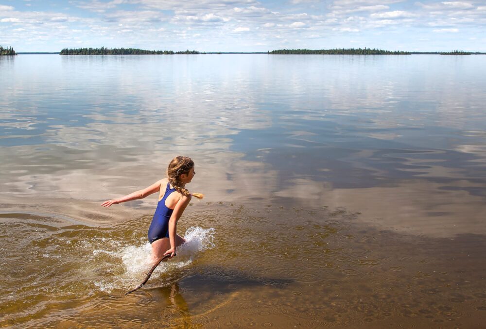 Girl splashes into a lake in summer.