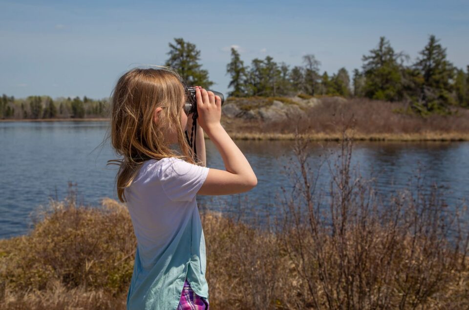 Young person looking through binoculars.