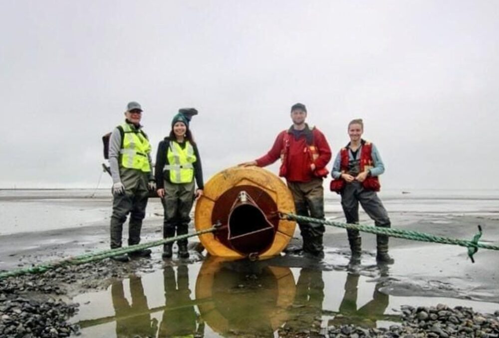 DUC CEO Michael Nadler, DUC Chief Marketing and Communications Officer Janine Massey, Lead Conservation Biologist Eric Balke, and Conservation Specialist Jamie Gauk stand on either side of the sediment delivery pipeline at low tide during the delivery window.