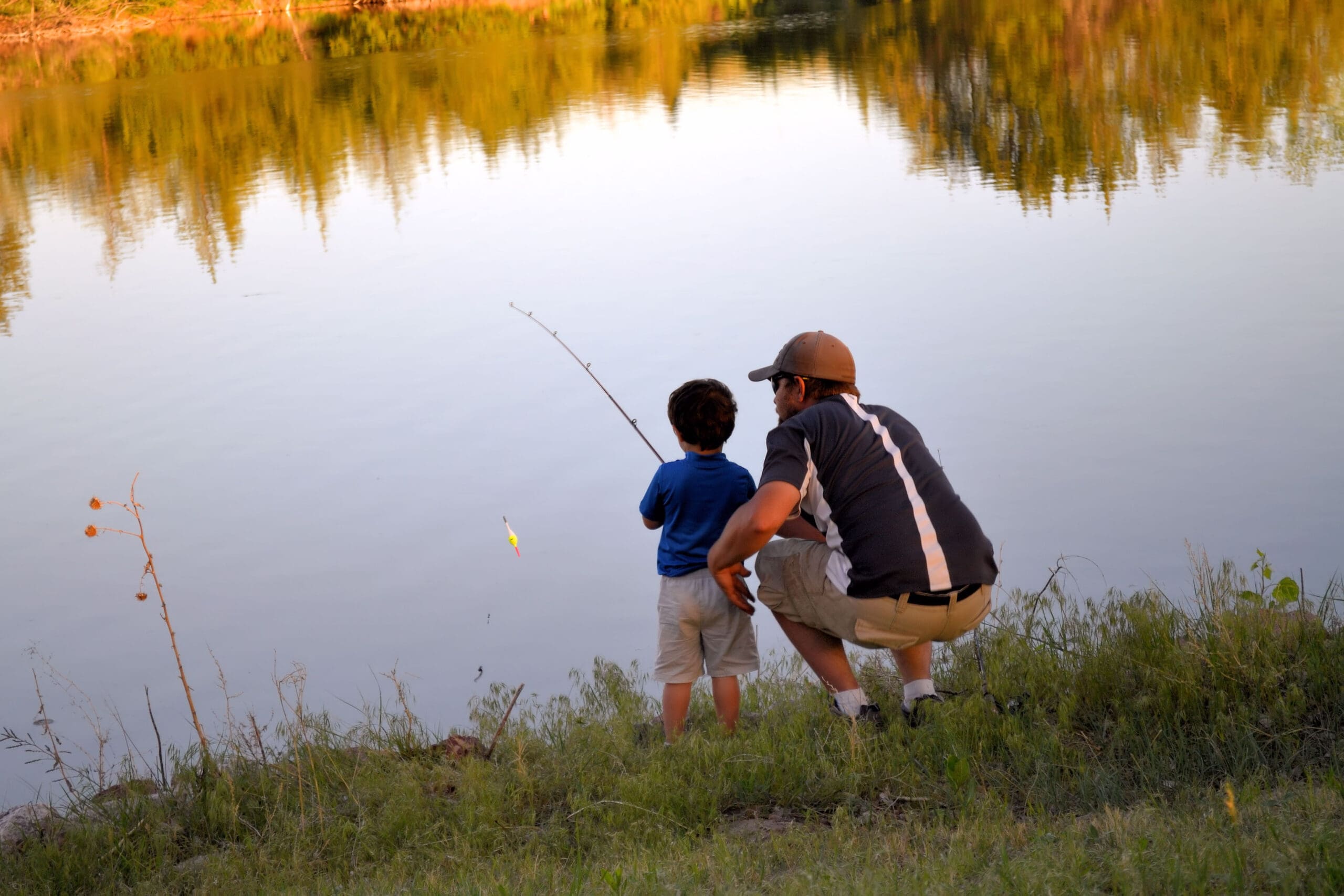 A father teaching his son how to fish from shore.