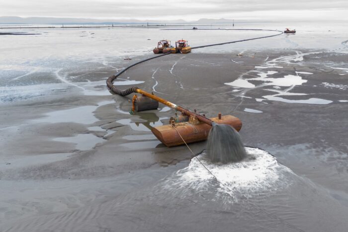 Work crews repurpose sediment dredged from the Fraser River and, using a large hose, place it in key areas on the bank. Waves, winds and tides will redistribute the sediment throughout the foreshore.  