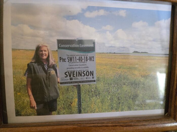 Jean Sveinson stands proudly next to the project sign that bears their name.