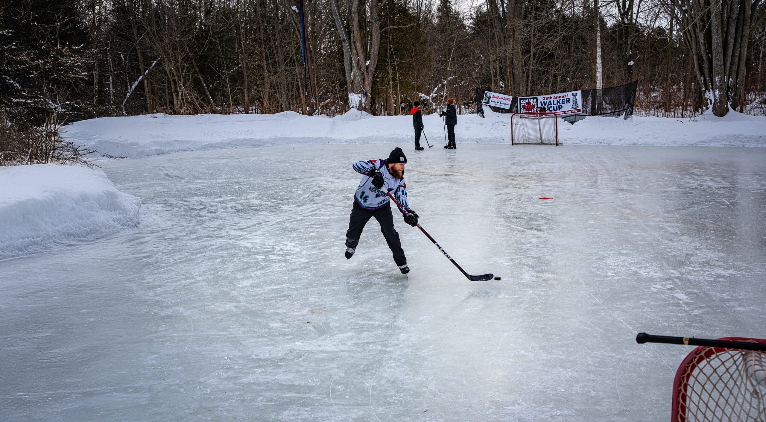 Two people playing pond hockey.