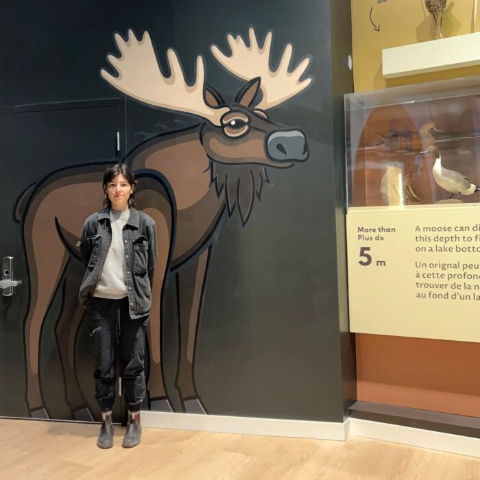Justine Proulx poses with her full-size moose depiction at the Wetland Discovery Centre.
