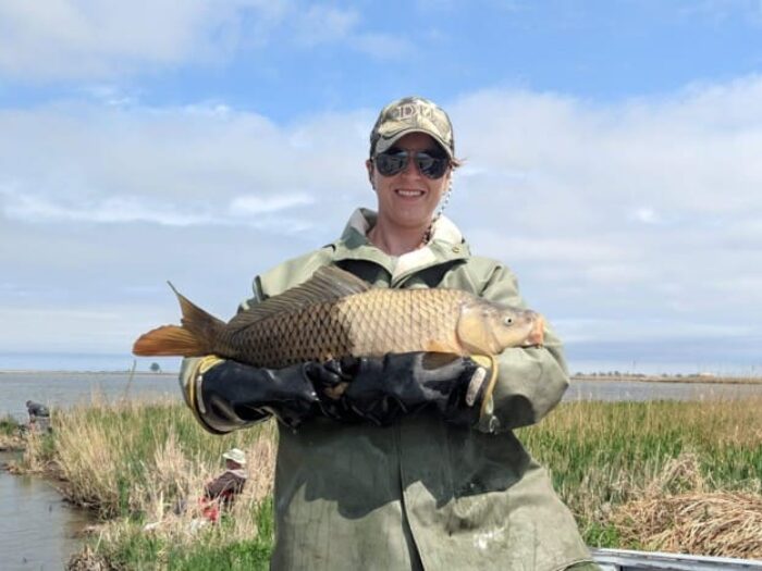 Paige Kowal holding a carp with odd scale colouring.