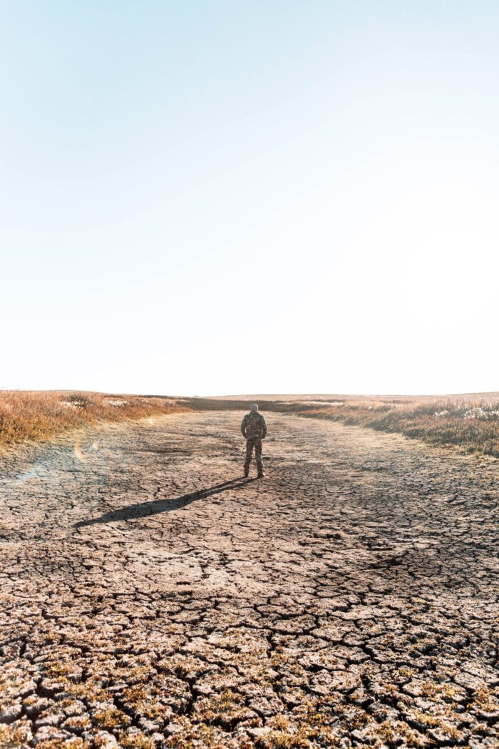 A hunter surveys a dried-up prairie pond.